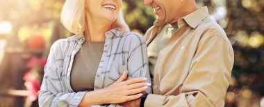 Neşeli bir çift, güneşli bir açık hava ortamında birbirlerine yakın durur. Gülücükler ve kahkahalar atarlar. Birlikte geçirdikleri günün tadını çıkarırken rahat ve mutlu görünüyorlar..