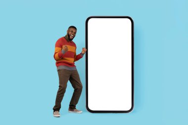 Harika bir teklif. Beyaz Ekranlı Büyük Boş Akıllı Telefon 'un yanında, Siyah Adam' ın Başarısını Kutluyor, Mutlu Afrikalı Genç Amerikalı Erkek Yumrukları ve Heyecanla Bağrışan, Sahte Görüntü