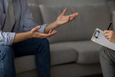 Rahat bir koltukta otururken psikoterapistle konuşan bir adam. Terapist dikkatle dinler, not alır. Sahnede profesyonel psikolojik yardım vurgulanıyor.