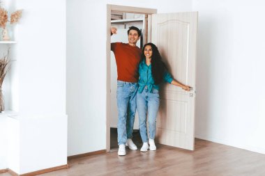 Bir çift yeni evlerinin kapısında sevinçle duruyor. Mutluluklarını paylaşıyorlar, yeni bir başlangıç için heyecanlılar. Şık iç mekan ve doğal ışık atmosferi güçlendirir..