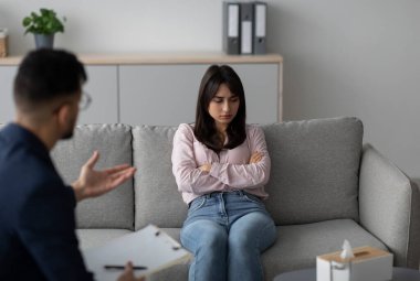 Genç bir Arap kadın doktor muayenehanesinde bir kanepede oturur, kollarını kavuşturup, yakınlarda oturan bir psikoloğun tavsiyelerini dinler. Atmosfer sakin ama ciddi..