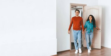 Bir çift yeni evlerine birlikte giriyor, gülümsüyor ve el ele tutuşuyorlar. İfadeleri, yeni başlangıçlarını keşfederken mutluluğu gösteriyor. İçerisi aydınlık ve misafirperver..