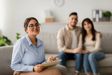 Mutlu bir Arap kadın evlilik danışmanı, ortadoğulu bir çiftle etkili bir terapi seansından sonra ofisinde güvenle gülümsüyor. Odada güven ve iletişim çok açık..