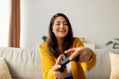 Neşeli bir ortadoğulu kadın evinde koltuğunda oturup, oyun oynayarak hafta sonunun tadını çıkarıyor. Gülümsüyor, oyun deneyimine kendini tamamen kaptırmış..