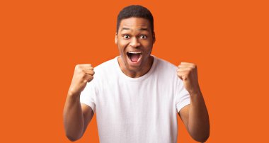 Büyük şans. Heyecanlı Afrikalı Amerikalı çocuk sevinçten çığlık atıyor. Kazanan jest yapıyor. Turuncu duvar, panorama, kopyalama alanı...