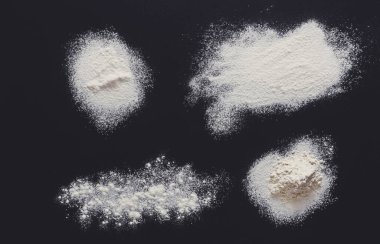 Siyah arka planda beyaz un lekeleri var. Karatahtanın en üst görüntüsü. Pişirme konsepti, hamur veya hamur işi.