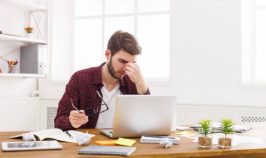 Göz ağrısı. Yorgun, işadamı ile laptop modern beyaz ofis iç overworking. Yakışıklı adam rahat ile bilgisayar, işyerinde iş sorunları kavramı.