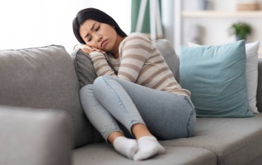 Depresyon Konsepti. Evdeki koltukta oturan üzgün Asyalı kadının portresi, ağlamaya hazır üzgün, kederli, kederli, kederli, umutsuz ve yalnız hisseden, yakın çekim,