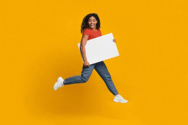 Kırmızı gömlekli ve mavi kotlu neşeli bir kadın elinde boş bir tabela tutarken koşuyor. Parlak sarı arka plan, sahnenin neşeli atmosferine ekleniyor..