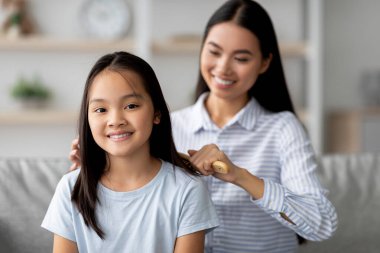 Sıcak bir oturma odasında, bir anne kanepede yan yana otururken kızlarının saçlarını nazikçe tarar. Genç kadın çocuğuyla ilgilenmekten zevk alıyor. Bir bağ kuruyor..