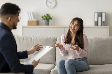 Sıcak bir ofiste, orta doğulu bir kadın duygularını bir psikologla tartışırken minnettarlığını ifade eder. Verimli konuşmaları sırasında heyecanlı ve meşgul görünüyor..