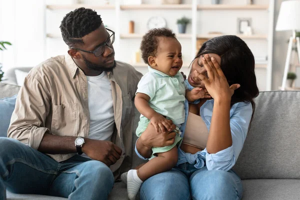 Ebeveynler rahat bir oturma odasındaki kanepede oturur ve anne ağlayan çocuğunu tutarken alnına dokunur. Baba, yorgunluklarının ortasında huzur verir..