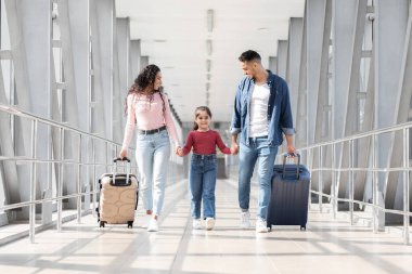 Üç kişilik bir aile, parlak bir havaalanı terminalinden el ele geçiyor. Dolaşan bavullar taşırlar ve yolculukları boyunca birbirlerine eşlik ederken gülümsemelerini paylaşırlar..