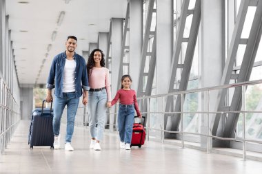 Üç kişilik bir aile şık bir havaalanı koridorunda el ele yürür. Bavul taşıyorlar ve günlük kıyafetler giyiyorlar. Birlikte yapacakları yolculuk için heyecanlılar..