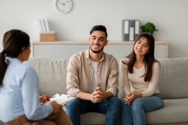Orta doğulu mutlu bir çift danışmanlık bürosunda bir kanepede oturur. Danışmanla iletişim kurarlar. Aile ilişkileri ve iletişim tavsiyelerini dikkatle dinlerken gülümserler..