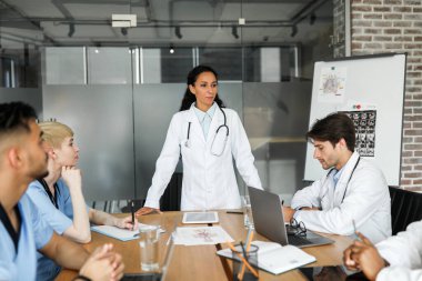 Orta Doğulu genç kadın başhekim, erkek ve kadın uluslararası meslektaşlarının önünde sunum yaparken, ekip oluşturma, sağlık personeli kısa ve öz konuşma, kopyalama...