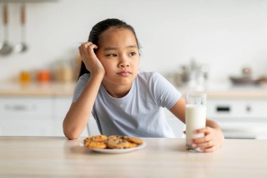 Üzgün Asyalı bir kız mutfak masasında oturuyor, elinde bir bardak sütle başka yere bakıyor. Kurabiyeler önüne konuyor. Mutfak ortamında sessizce rüya görüyor..