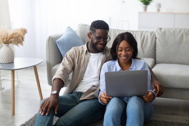 Genç bir Afro-Amerikan çift, rahat oturma odalarında yerde oturup dizüstü bilgisayarlarında mutlu bir şekilde film izliyorlar. Nişanlandılar ve hafta sonu birlikte vakit geçiriyorlar..