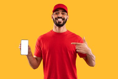 Kırmızı tişörtlü ve şapkalı neşeli bir genç adam boş ekranlı bir akıllı telefonu işaret ediyor. Parlak sarı arka plan sahneye enerji katıyor..