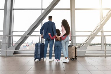 Bir aile havaalanında birlikte duruyor, yolculuklarını sabırsızlıkla bekliyorlar. Büyük pencerelerin dışındaki uçakları izlerken kucaklaşıyorlar. Bagajları kalkışa hazır..