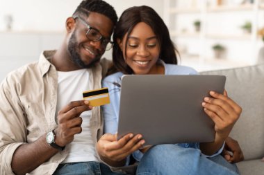 Milenyum siyahi çifti evlerindeki kanepede yan yana oturur. Ürünleri heyecanlı bir şekilde çevrimiçi seçiyorlar, bir ortak banka kartını tutuyor ve diğeri de dizüstü bilgisayarın ekranına bakıyor.