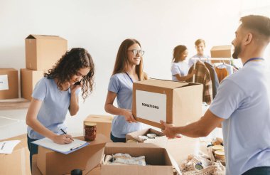 Bir grup gönüllü, bağışları düzenlemek ve sıralamak için, parlak bir toplum merkezinde birlikte çalışıyorlar..