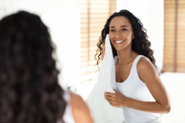 Bir kadın yüzünü yıkadıktan sonra nazikçe havluyla kurulamaktan zevk alır. Doğal ışık, sakin banyo ortamındaki özelliklerini vurguluyor..