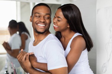 Parlak banyolarında bir çift sıcak bir kahkahayı paylaşıyor. Birbirlerine uyumlu beyaz kıyafetler giyiyorlar, önlerindeki güne hazırlanırken birbirlerine eşlik etmekten zevk alıyorlar..