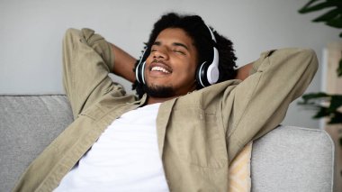 Afro-Amerikalı bir adam evdeki koltukta kablosuz kulaklık takarak rahatça oturuyor. Kapalı gözlerle gülümsüyor, en sevdiği müziğe dalmış ve boş zamanlarının tadını çıkarıyor..