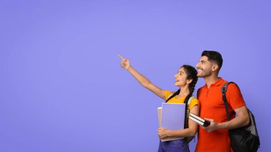 İki arkadaş yan yana durur, gülümser ve ilginç bir şeye bakarlar. Heyecanlarını vurgulayan parlak mor bir arka planı olan kitaplar ve defterler tutuyorlar..