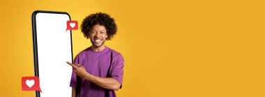 Bir adam parlak sarı bir arkaplana karşı duruyor, boş bir akıllı telefon ekranını işaret ederken gülümsüyor. Kalpleri olan konuşma baloncukları görülebilir..