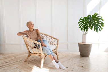 Evdeki hasır koltukta oturan kaygısız genç bayan fotokopi odasına bakıyor ve gülümsüyor. Güzel kadın hafta sonunu yalnız geçiriyor.