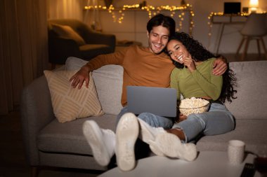 Mutlu bir çift düşük ışıkta kanepede oturur ve dizüstü bilgisayarlarında film izlerler. Bir kase patlamış mısırı paylaşıyorlar, rahatlar ve evlerinde keyifli bir akşam geçiriyorlar..