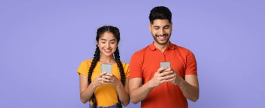 İki genç arkadaş yan yana durur, akıllı telefonlarıyla meşgul olurken gülümserler. Parlak mor bir arkaplan önündeler, canlı bir bağlantı ve eğlence anı sergiliyorlar..