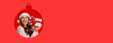 Noel Baba şapkası takan neşeli bir kadın elinde hediyeyle gülümsüyor. Parlak kırmızı arka plan, bayramları kutlamak için mükemmel bir şenlik atmosferine ekleniyor..