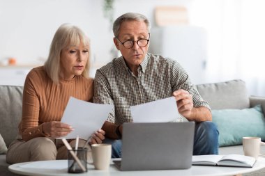 Yaşlı bir çift oturma odalarındaki bir kanepede oturup belgelere yakından bakıyor. Sıcak bir atmosferle çevriliyken, düşüncelerini ve fikirlerini dikkatlice gazetelere aktarıyorlar..