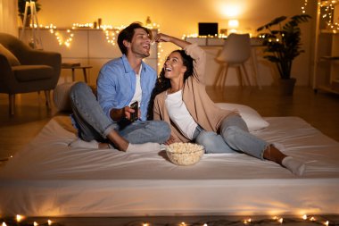 Neşeli çift modern yatak odalarında battaniyeye sarılıp birbirlerini patlamış mısırla besliyor. Film izlerken birbirlerine cilveli gülücükler saçıyorlar, rahat bir hafta sonu ortamı yaratıyorlar..