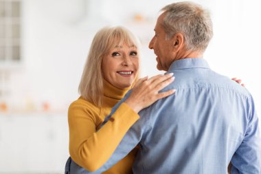 Neşeli bir son sınıf çifti sıcak mutfaklarında dans etmekten zevk alır. Kadın, ortağına bakıp sıcak bir atmosfer yaratırken ışıl ışıl gülümsüyor..