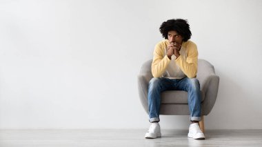 Genç bir Afrikalı Amerikalı adam rahat bir koltukta oturuyor, tedirgin bir ifadeyle yan tarafa bakıyor. Düşüncelere dalmış gibi görünüyor, sakin bir iç mekanda zor bir seçimle karşı karşıya..