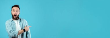 Bir adam sersemlemiş bir bakışla, gözleri kocaman ve ağzı açık durur. Tarafını gösteriyor, önemli ya da şaşırtıcı bir şey gösteriyor. Arka plan parlak bir mavi..