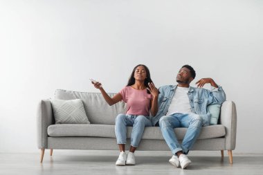 Sistemi böl. Binlerce yıllık terli siyahi erkek ve kadın yaz sıcağından muzdarip, terli kadın uzaktan kumandayı çalıştırıyor, aile oturma odasında kanepede oturuyor, bedava fotokopi odası var.