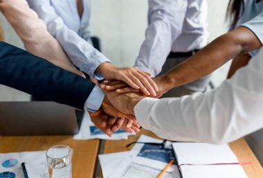 Başarılı bir şirket toplantısından sonra çeşitli meslektaşlar ellerini bir ofiste birleştirerek birleşiyorlar. Bu an takım çalışmasını ve profesyoneller arasında paylaşılan başarıyı simgeliyor..