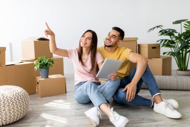 Sıcak, aydınlık bir odada, genç bir çift taşınan kutuların arasında yerde oturuyor. Birlikte rahatlarken tabletteki bir şeyi işaret ederek bir neşe anı paylaşırlar..