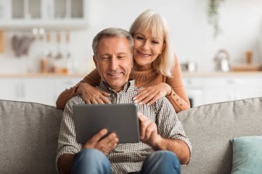 Üst düzey bir çift koltukta oturuyor, parlak, davetkar bir oturma odasında bir tabletle mutlu mesut meşgul oluyorlar. Sıcak evlerinde kahkaha ve neşe paylaşıyorlar..