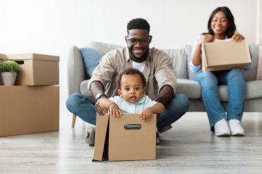 Üç kişilik siyah bir aile yeni evlerinde taşınmaktan zevk alıyor. Baba çocuğunu karton bir kutuya koyar ve anne mutlu bir şekilde yeni başlangıcını kutlar..