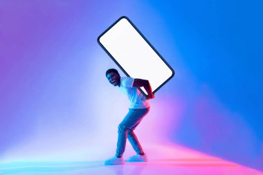 Neşeli bir yüzü olan bir adam arkasında büyük boş bir ekran taşıyor. Renkli ışıklandırma hareketli bir atmosfer yaratır, neşeli sahneyi güçlendirir..