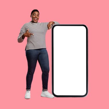 Neşeli bir kadın büyük boş bir akıllı telefon ekranının yanında duruyor. Çizgili bir kazak ve kot pantolon giyiyor, gülümsüyor ve el hareketleriyle izleyicileri kendine çekiyor. Arkaplan parlak pembe bir renk..