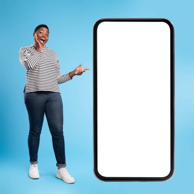 Neşeli bir birey boş bir akıllı telefonun yanında duruyor, mavi bir arkaplana bakıp gülümsüyor. Sahne heyecan ve bağlılık hissi veriyor..