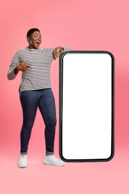 Bir insan çizgili gömlek ve kot pantolon giyerken boş bir akıllı telefon çerçevesiyle gülümsüyor. Arka plan canlı bir pembe. Sahneye eğlenceli ve yaratıcı bir hava katıyor..