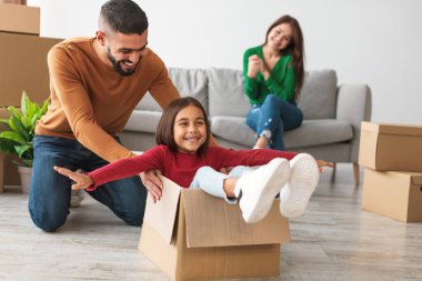 Mutlu bir Arap baba küçük kızıyla oynar, onu karton bir kutuya koyar. Neşeli anneleri onları izliyor, yeni evlerinde taşınma gününün heyecanını kutluyor..